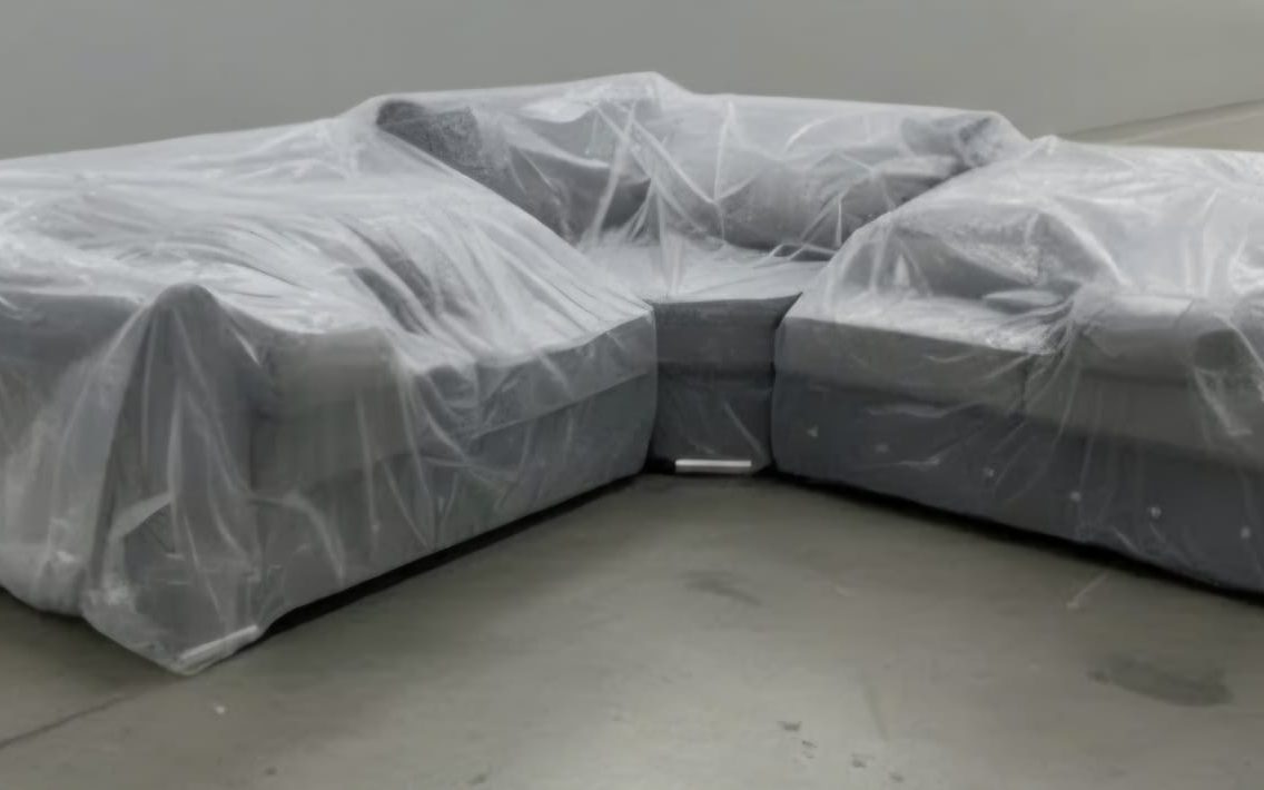 A corner sofa wrapped in clear protective polythene furniture covers