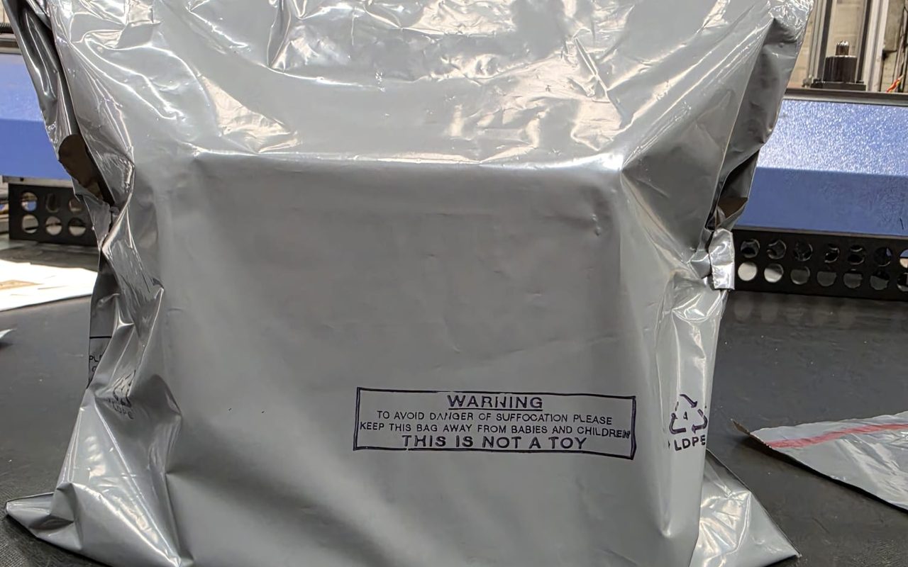 A filled and sealed grey polythene mailing bag on the packing bench at our Blackburn factory